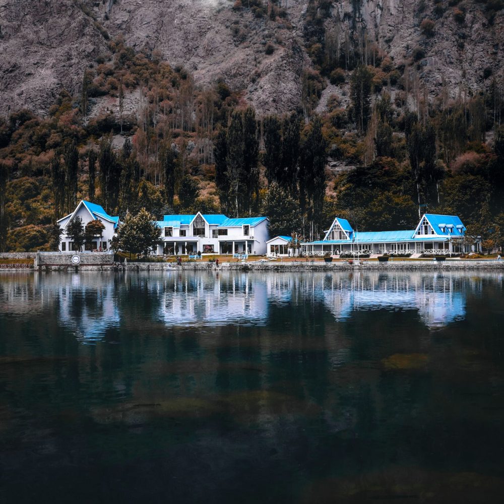 Captivating shot of houses by Skardu lake reflecting the serene mountain backdrop, perfect for travel and nature lovers.
